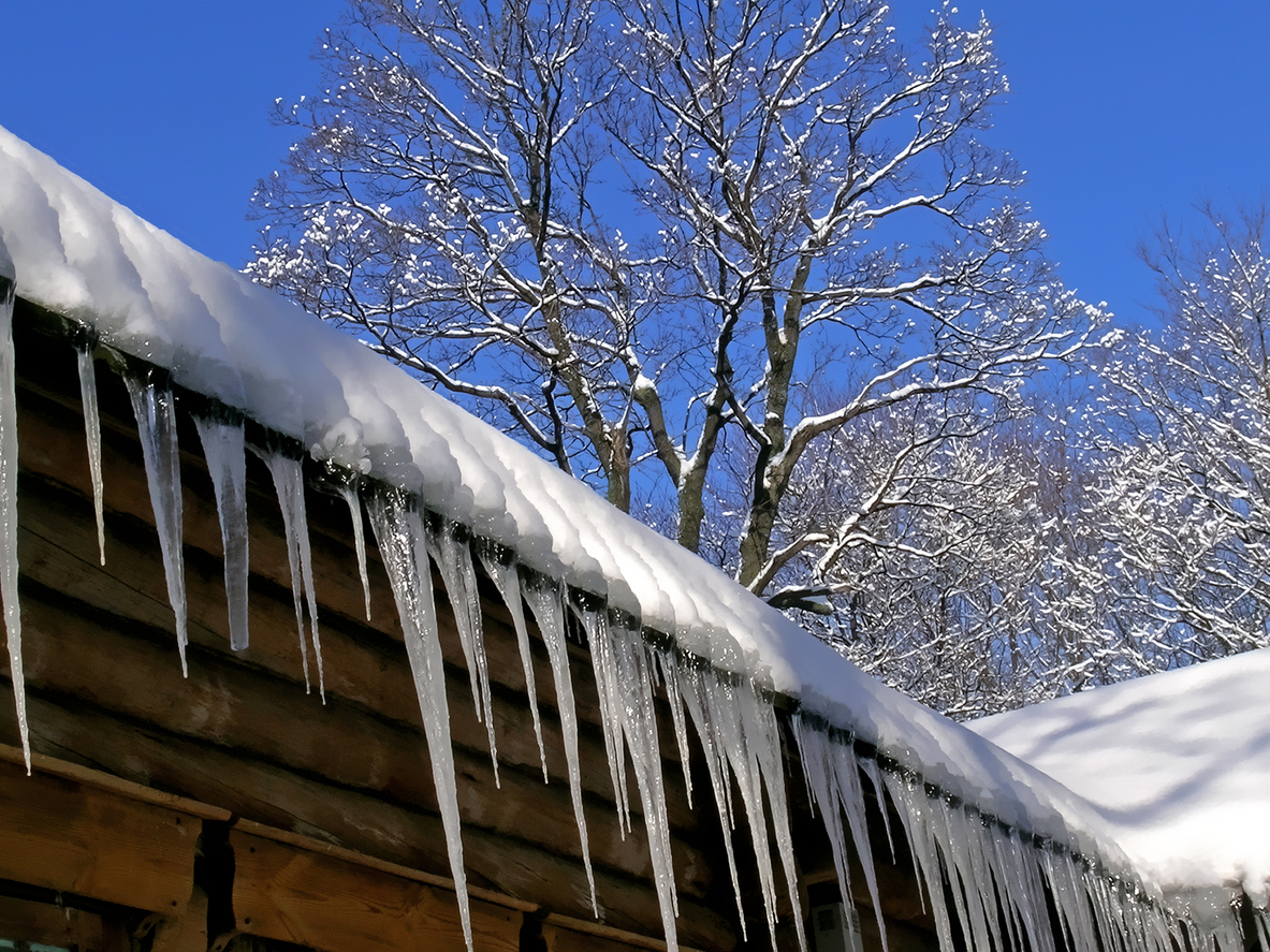 Icicles on the roof of the wooden house.