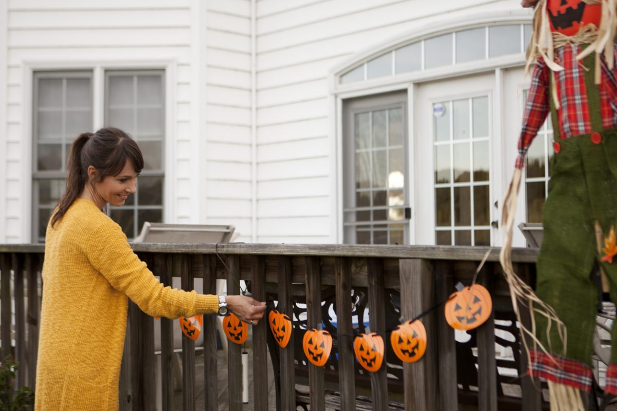 Women decorating around house for Halloween.