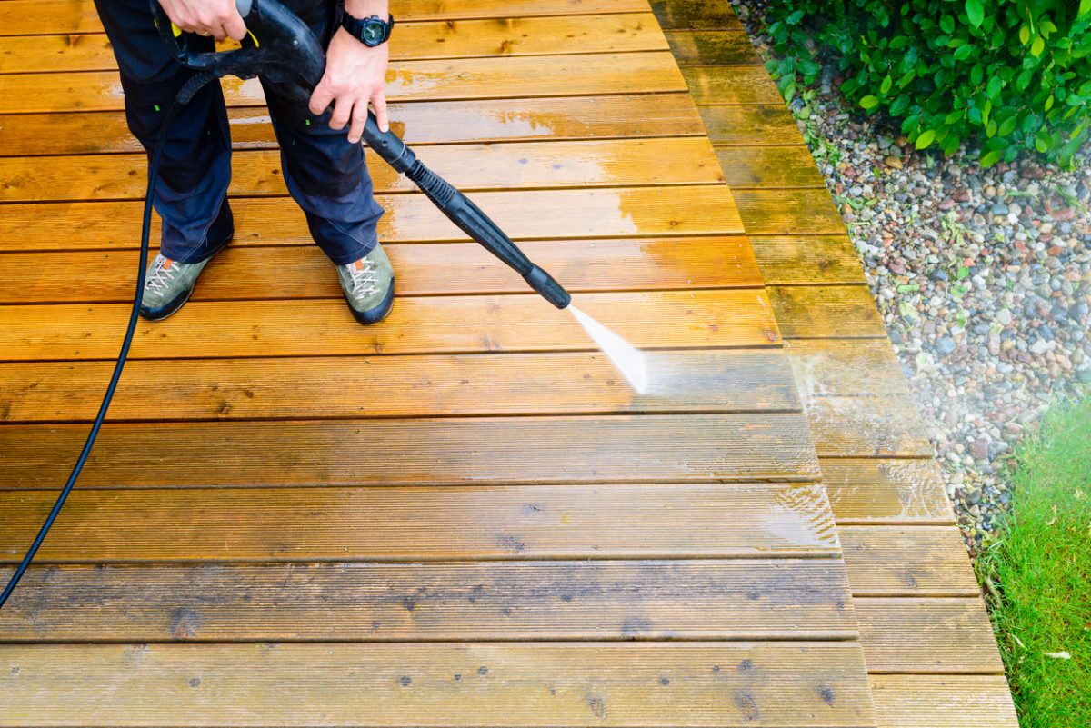 cleaning terrace with a power washer - high water pressure cleaner on wooden terrace surface