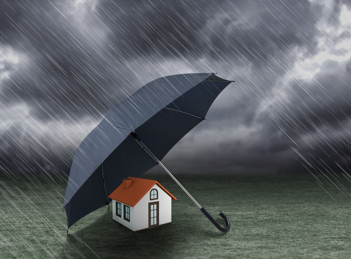 umbrella covering home under heavy rain, insurance concept