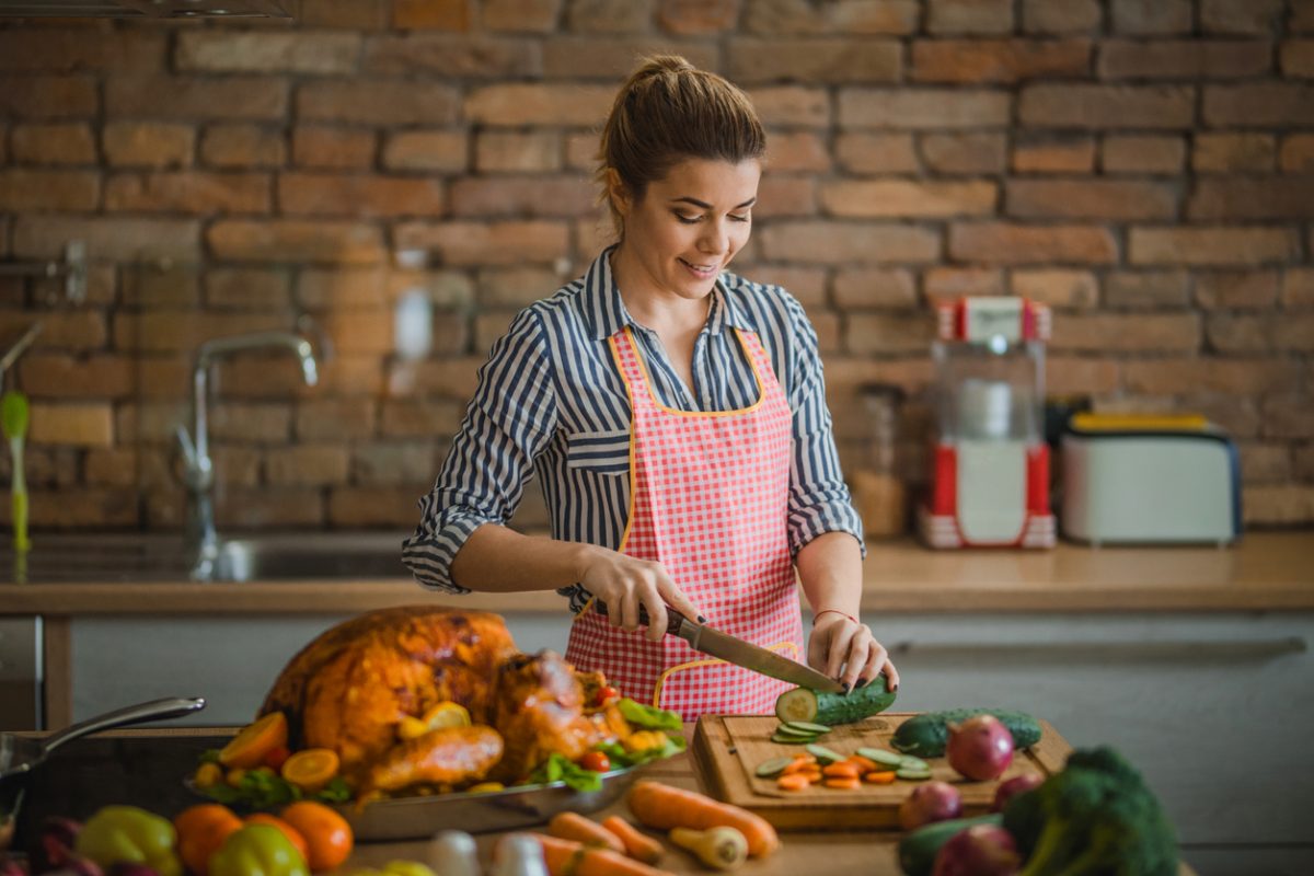 Young happy woman preparing salad for Thanksgiving meal at home.