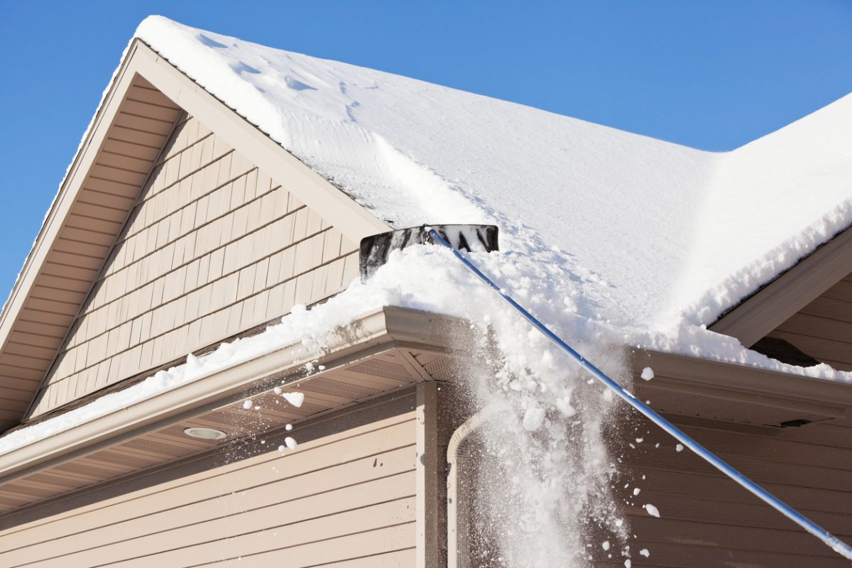 A roof rake is being used to remove snow from a winter roof. Large amounts of snow are often removed, using this method, to prevent ice dams and reduce excess weight. Ice dams form when melted roof snow freezes at the gutter sometimes leading to damage to the roof edge.