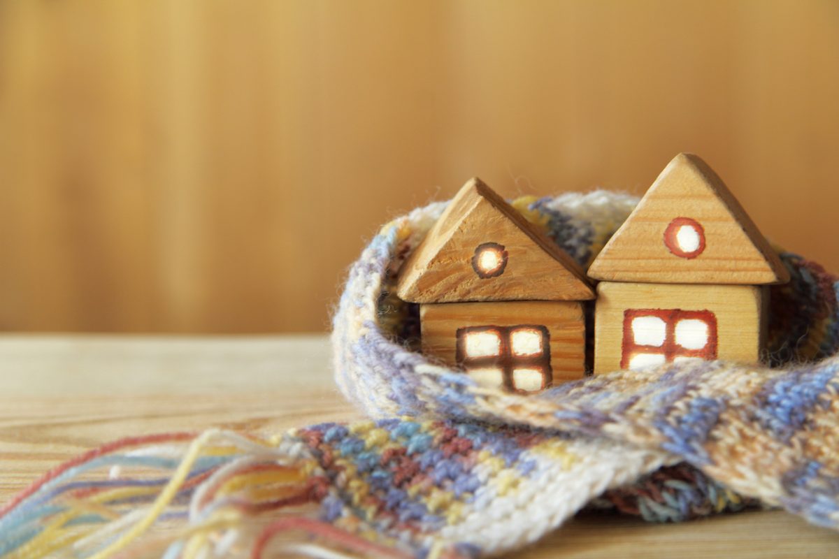 Two small wooden houses with light in the windows are covered with a large scarf