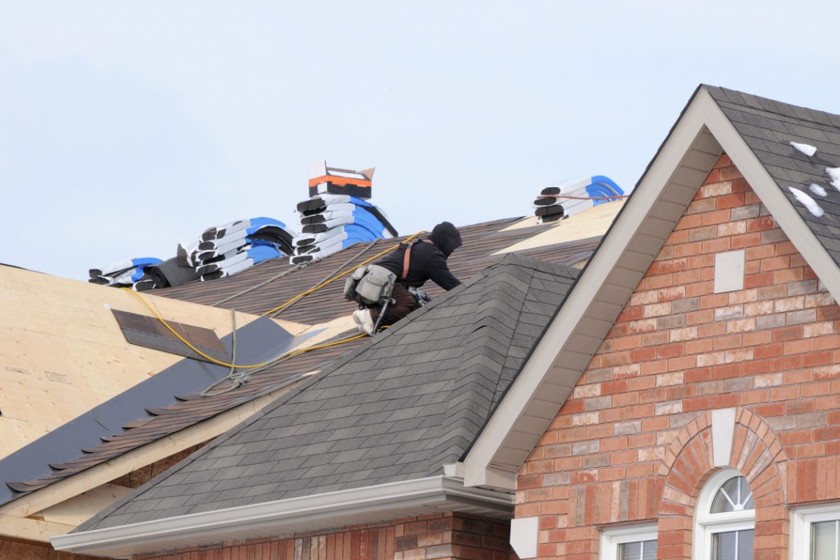 Roofer installing new asphalt shingles