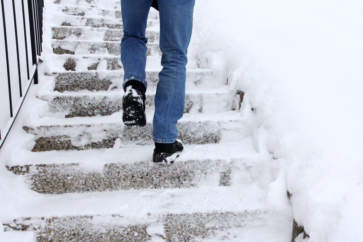 Risk of slipping when climbing stairs in winter. A man goes up a snow-covered staircase