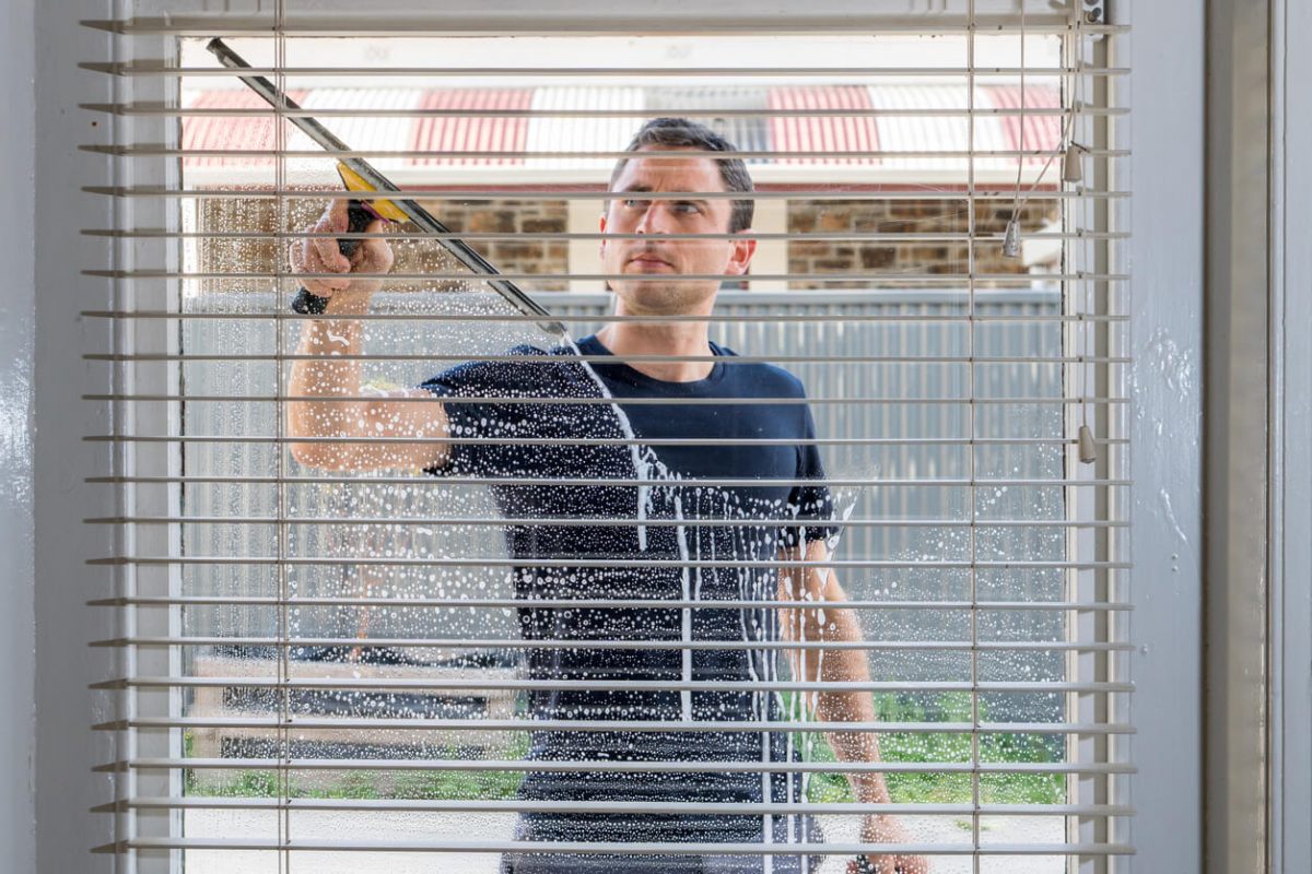 Inside view of a man washing the windows of a house