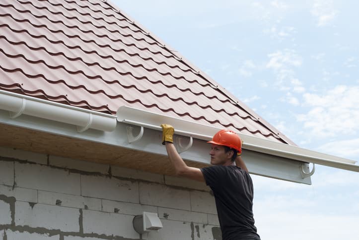 A worker installing gutters on a home