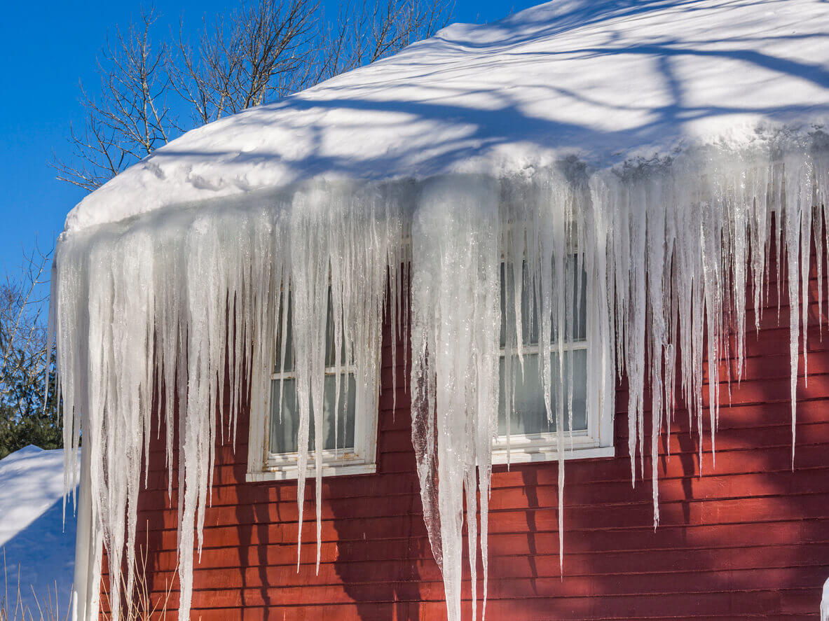 Ice dams and snow on roof and gutters after bitter cold in New England, USA