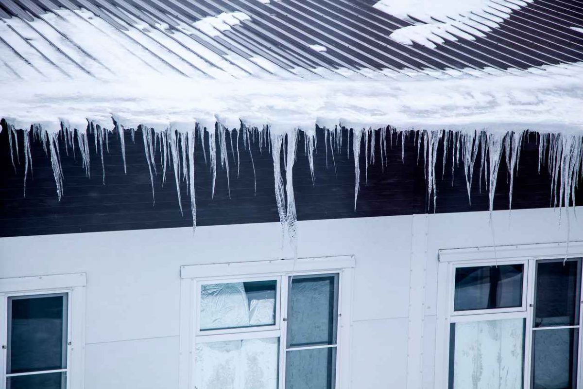 Ice dam hanging off metal roof, Winter threats, the threat of falling icicles from the roofs of buildings