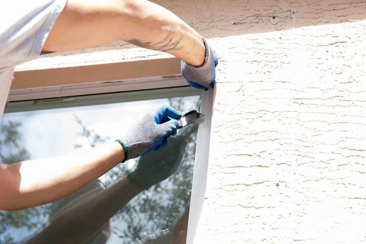 A real worker is using a hammer and crowbar to remove a window; Window Replacement vs. Repair